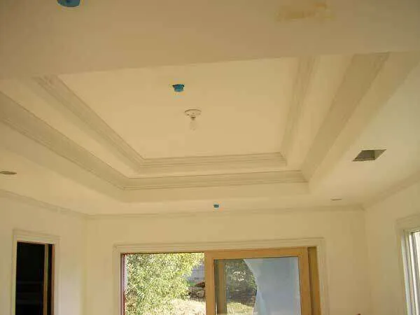 Interior room with coffered ceiling and recessed lighting, large window with wooden frame.