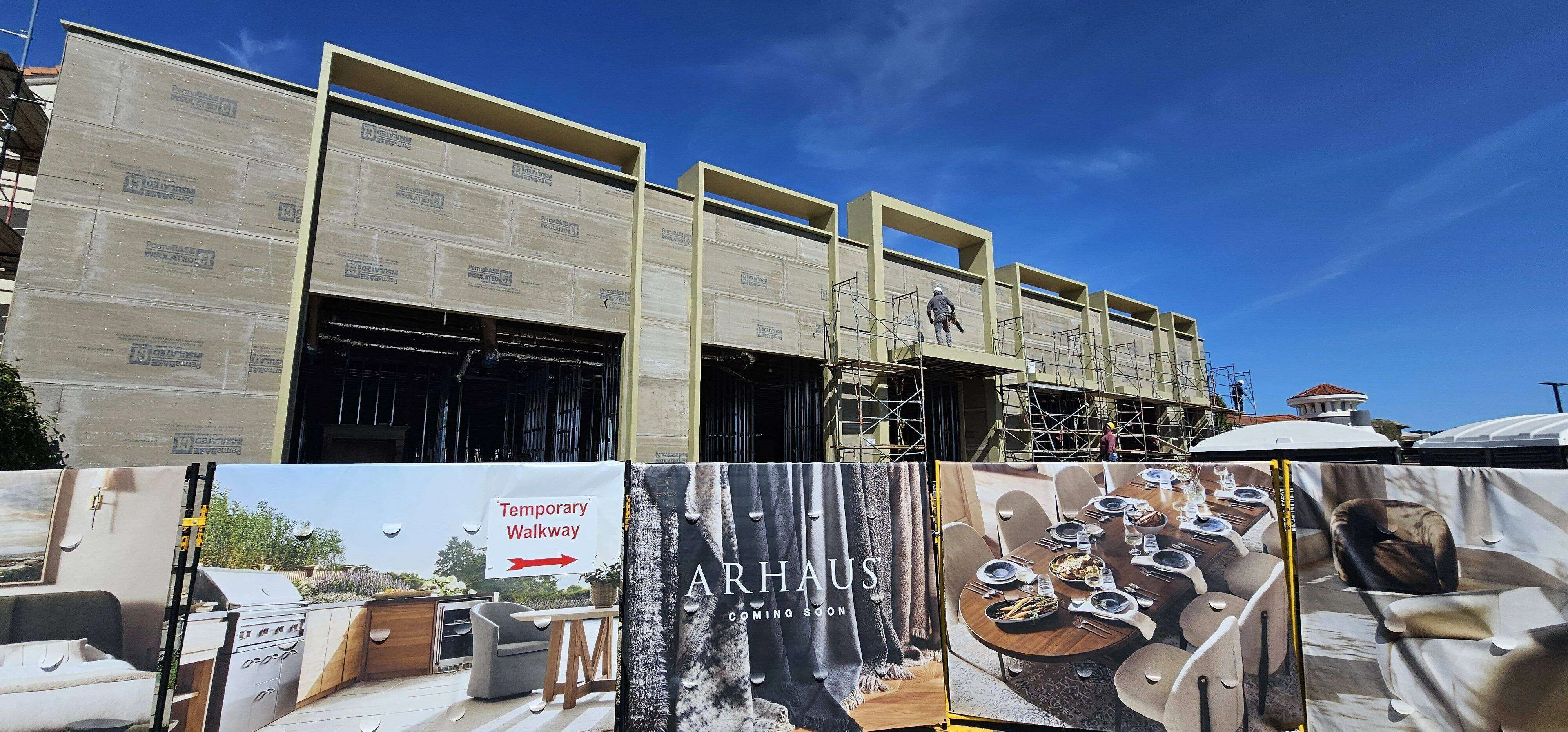 Commercial building under construction with scaffolding and temporary walkway sign.