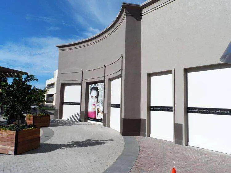 Commercial building with smooth EIFS finish and closed storefronts under a clear sky.