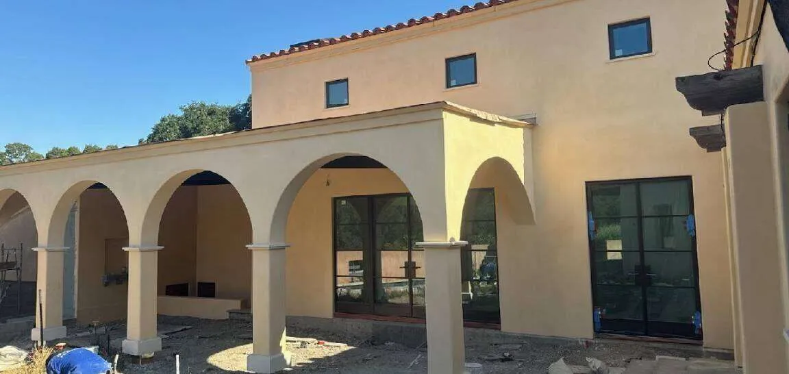 Commercial building with stucco exterior, arches, large windows, and tiled roof.