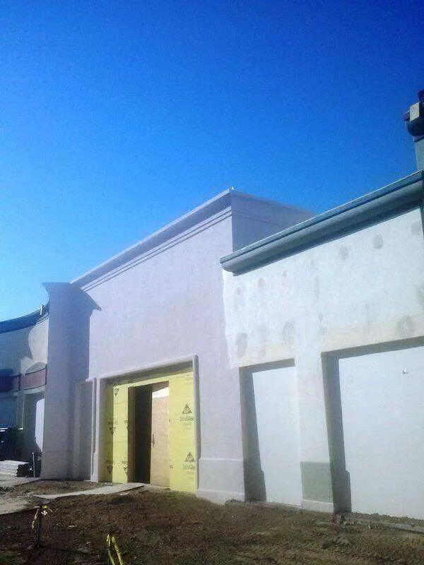 Commercial building with EIFS exterior under construction, showing insulation panels around entrance.