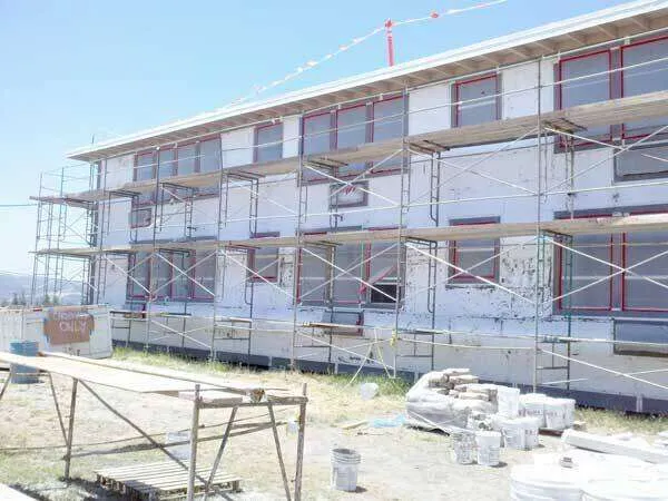 Scaffolding on a multi-story building with EIFS application in progress.