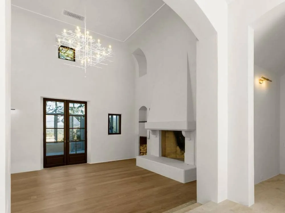Spacious room with chandelier, fireplace, wooden floor, and French doors in Saint Helena.