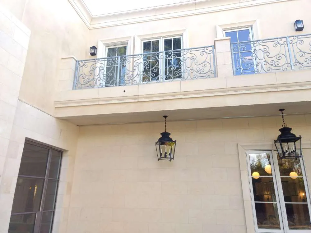 Exterior view of a residence with a balcony, metal railing, and hanging lanterns.