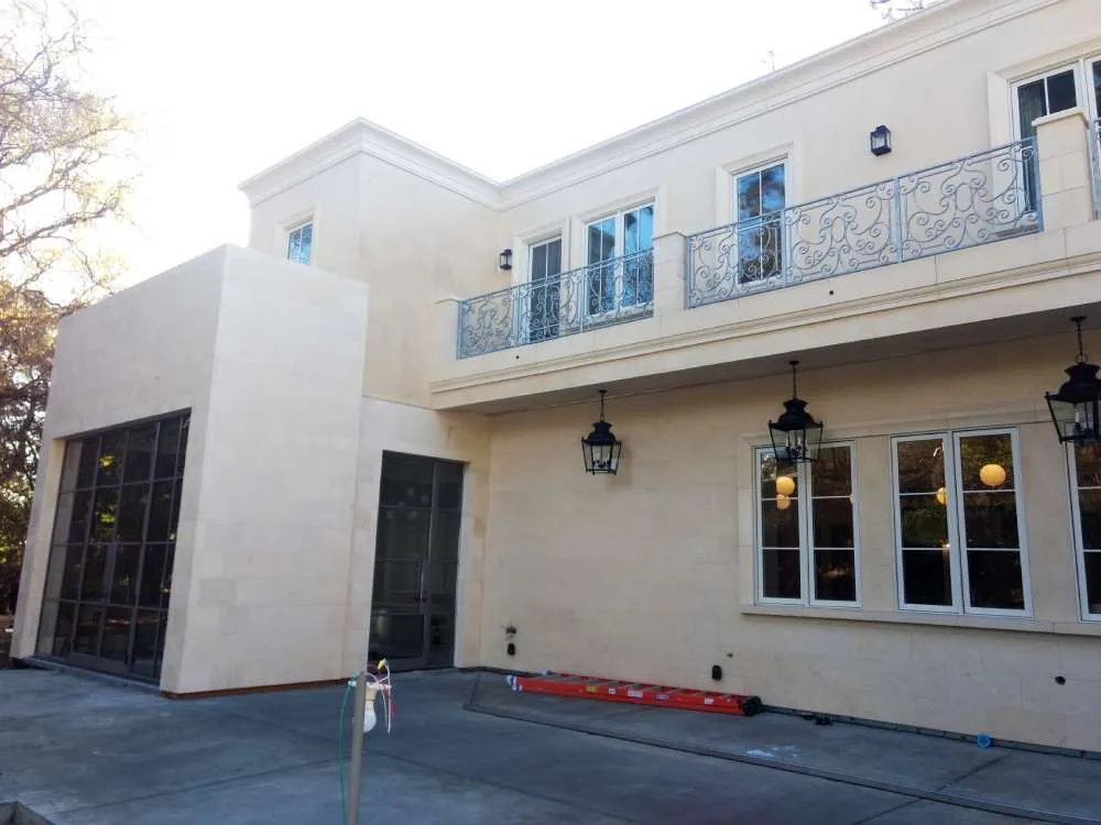 Two-story home with smooth stucco finish, large windows, and metal railings.