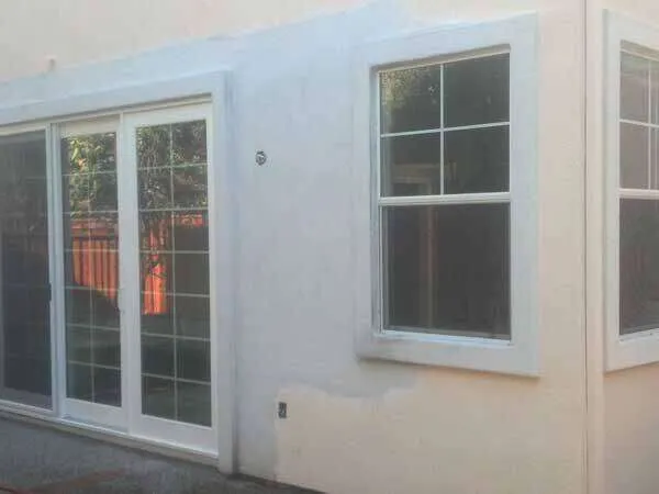 Residential exterior with foam trim around window and sliding door, partially finished.