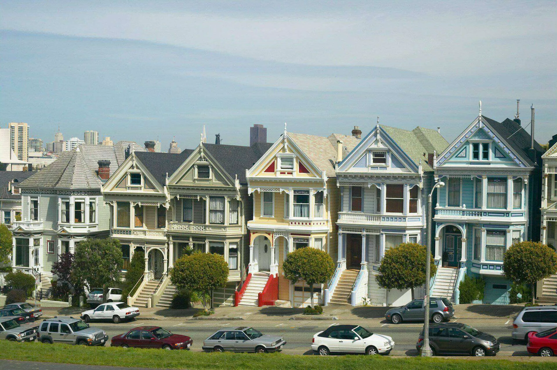 Row of colorful Victorian houses with city skyline in background, known as the Painted Ladies in San Francisco.