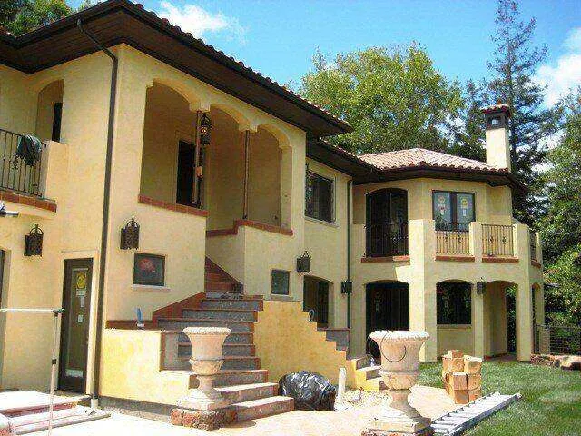 Mediterranean-style home with smooth stucco finish, arched entryways, and balconies.