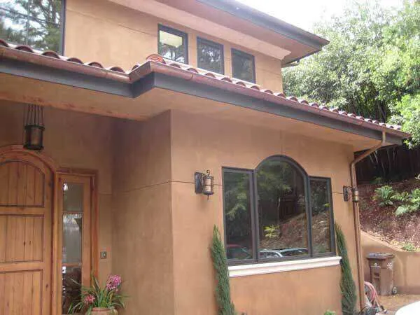 House exterior with smooth plaster finish, arched windows, and tiled roof.