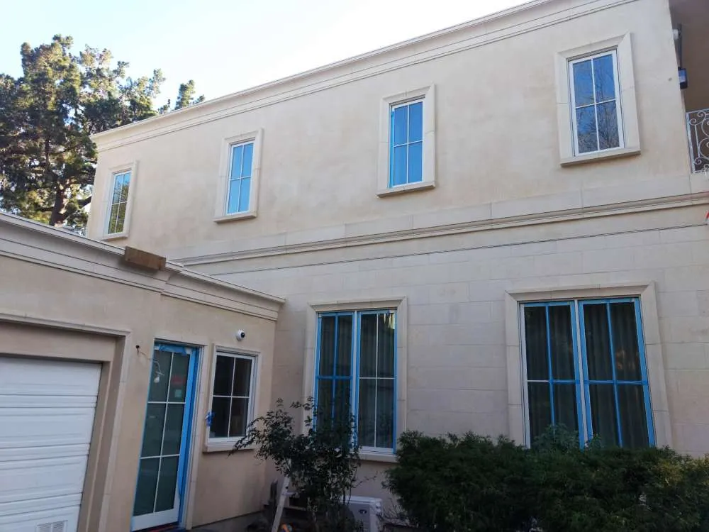 Two-story house with smooth stucco finish and blue-framed windows in Hillsborough.