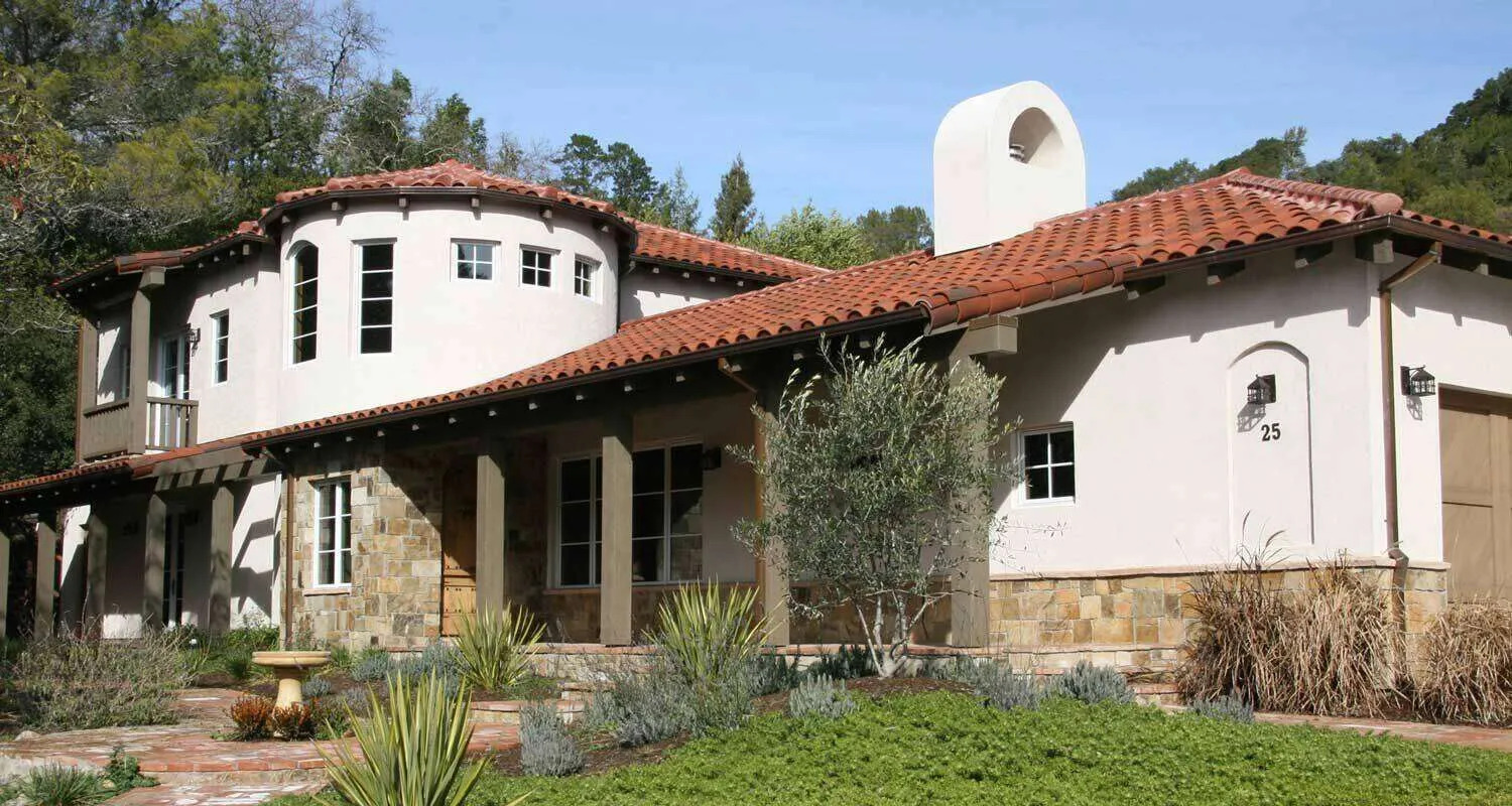 Mediterranean-style home with stucco walls, red tile roof, and arched windows in a landscaped setting.