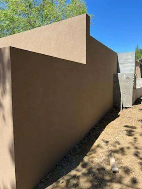Smooth-finished concrete retaining wall in an outdoor area with clear sky.