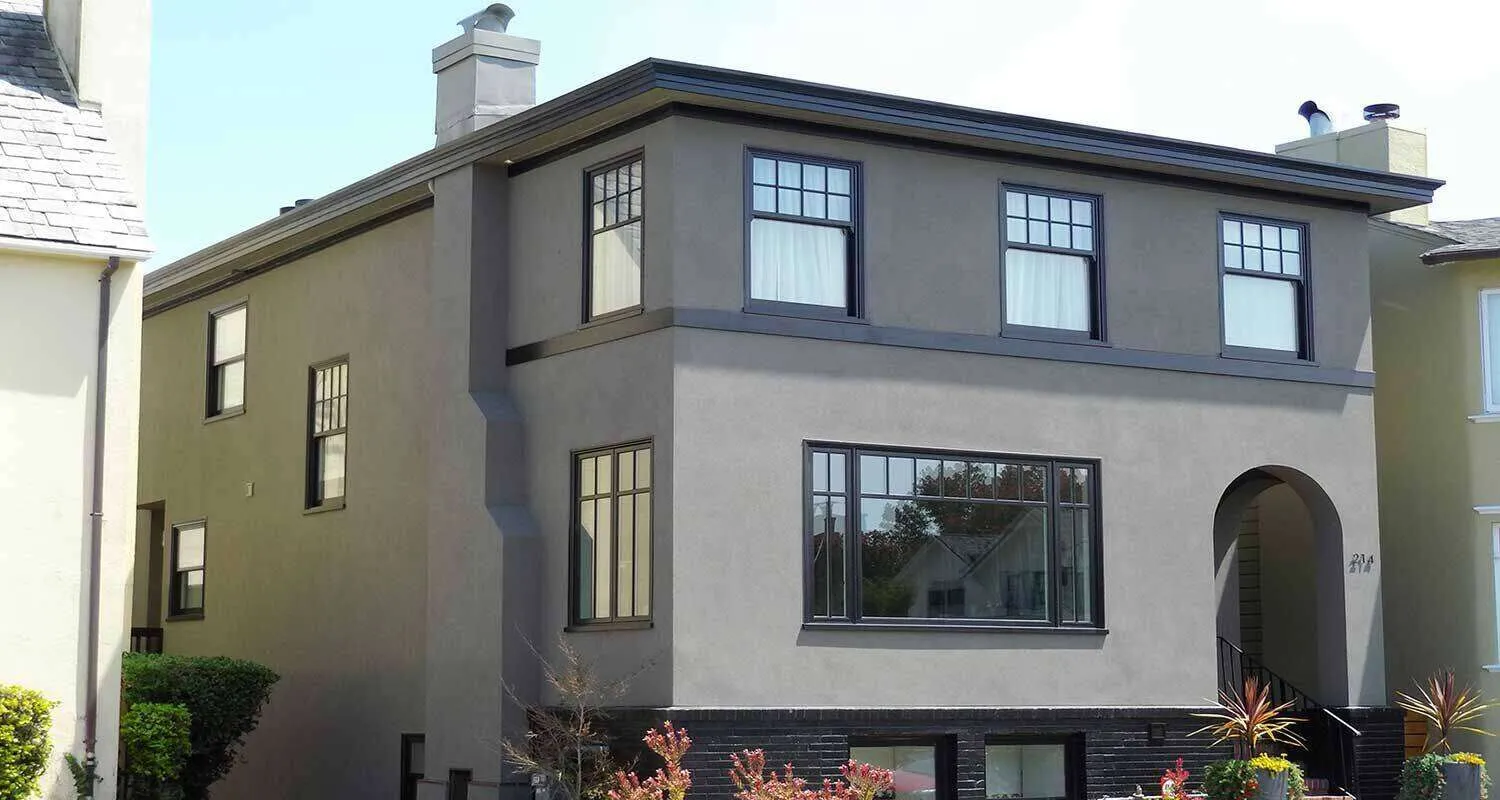 Two-story house with smooth stucco finish and black window frames.