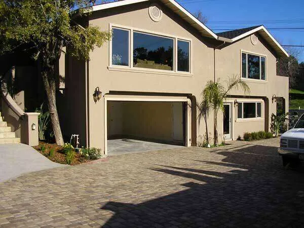 Two-story stucco home with large windows and paved driveway in Greenbrae.
