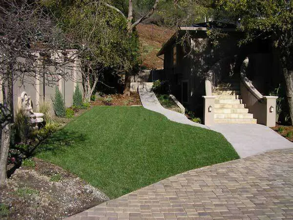Stucco home in Greenbrae with landscaped yard, stone steps, and paved driveway.