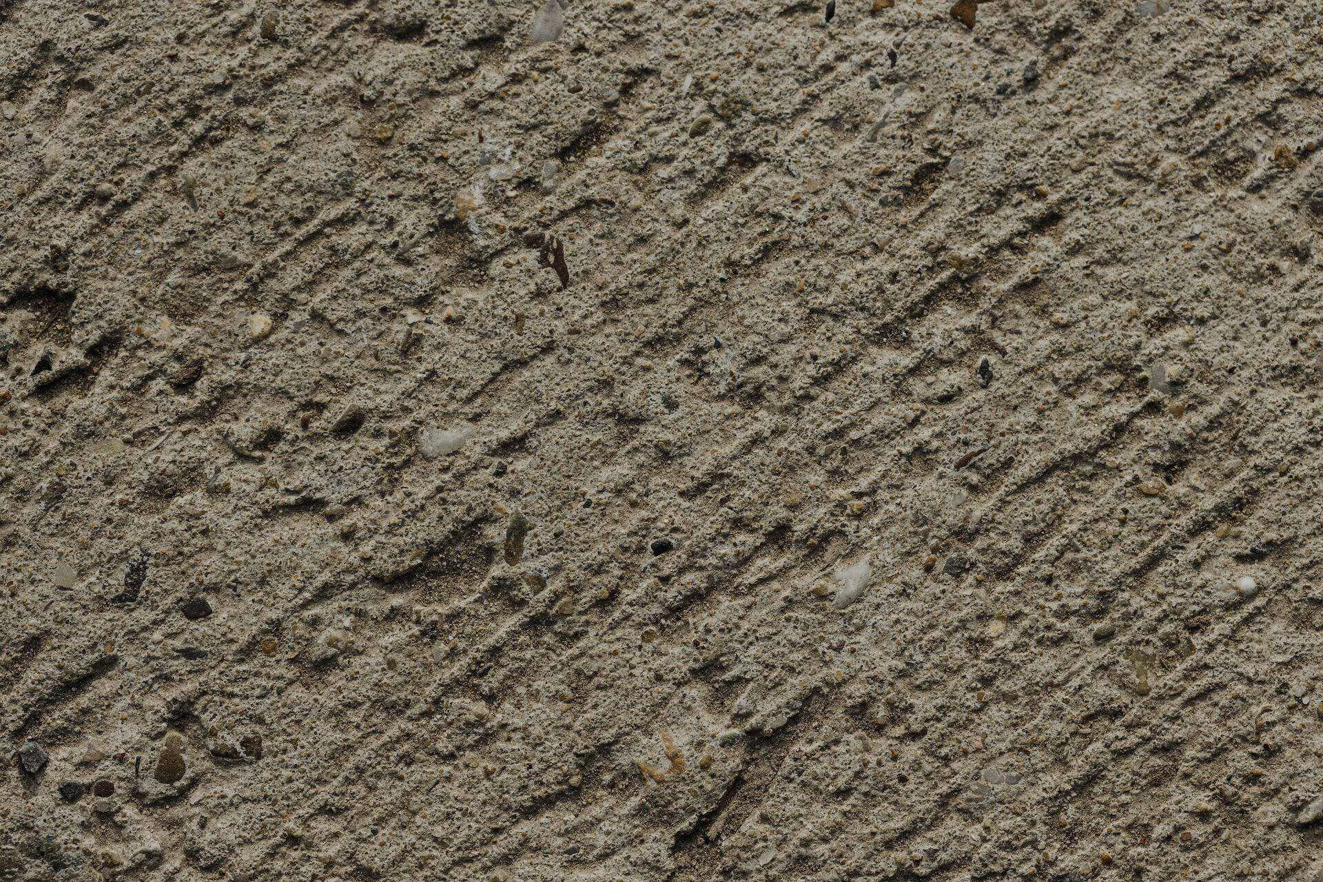 Close-up of a textured concrete surface with visible aggregate and diagonal lines.